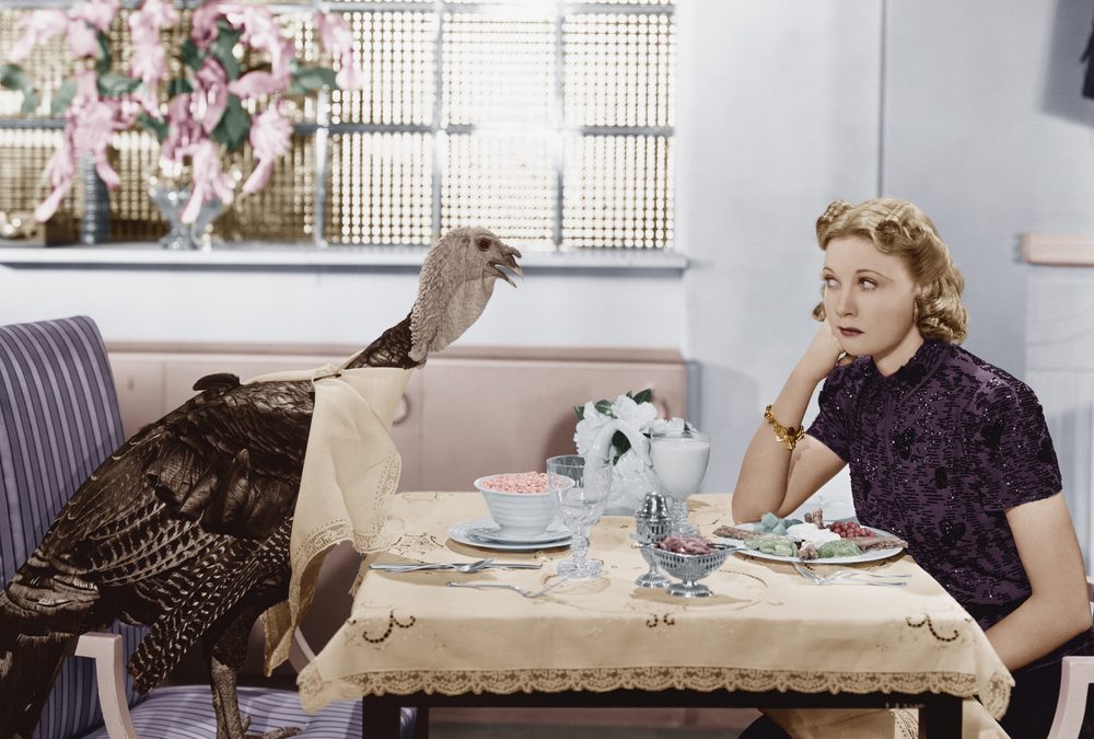 Woman eating meal at table with live turkey