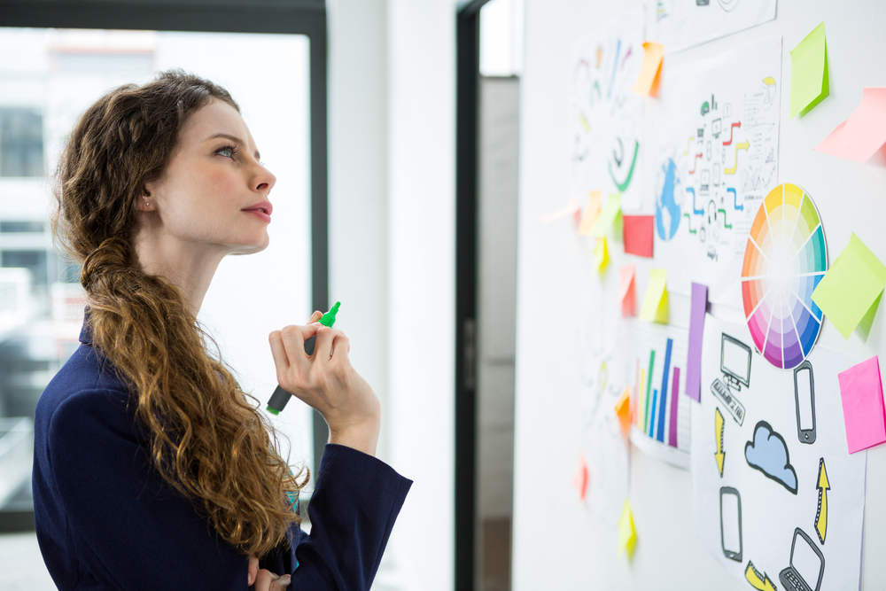 Thoughtful woman looking at adhesive notes in creative office