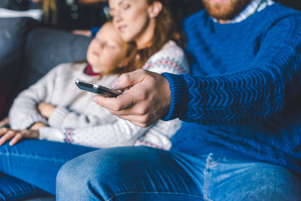 Family on couch watching television at night.