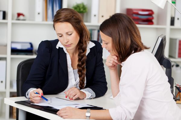 Image of two female co-workers having a discussion on a project.