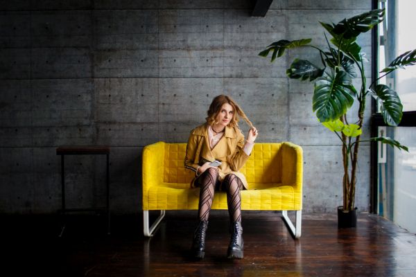 Young woman on yellow couch in barren apartment.