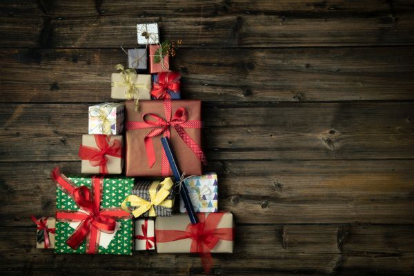 Generic holiday gifts arranged in the shape of a tree, on a distressed wood table.