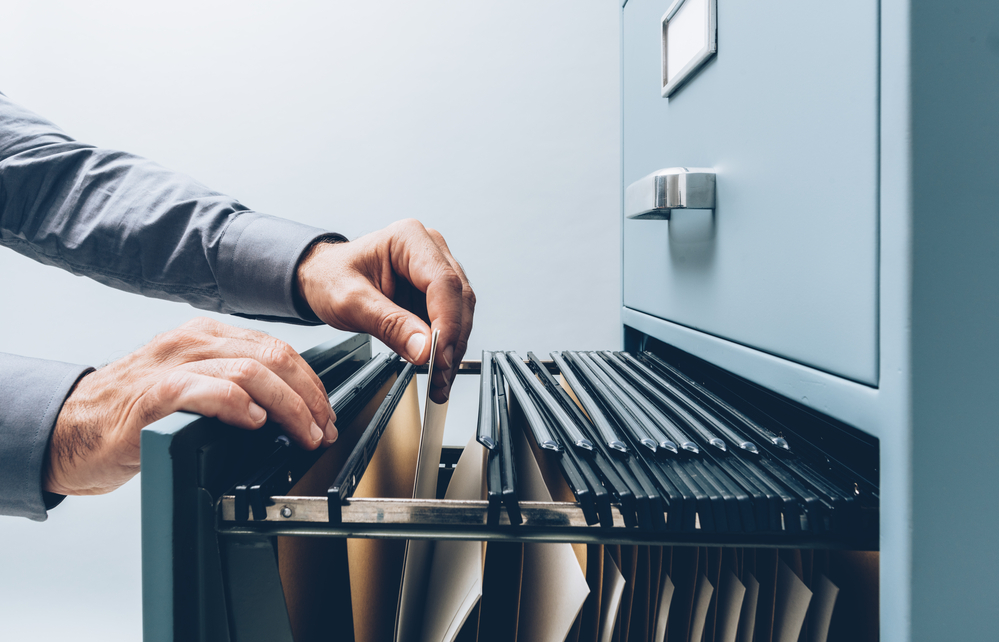 Office clerk searching for files into a filing cabinet drawer close up, business administration and data storage concept