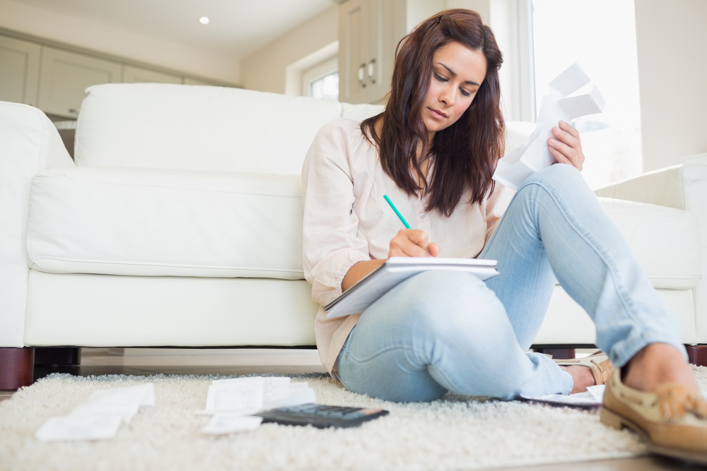 Young woman working out finances on floor of living room