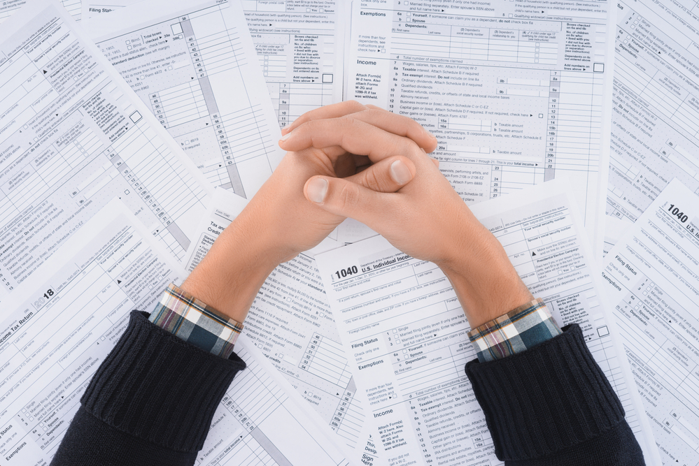 A woman's hands triumphantly folded over dozens of tax forms.