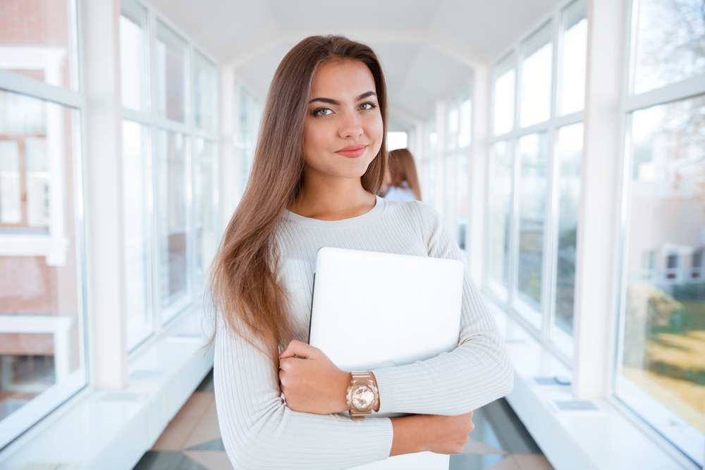 Young woman clutching her laptop protectively.